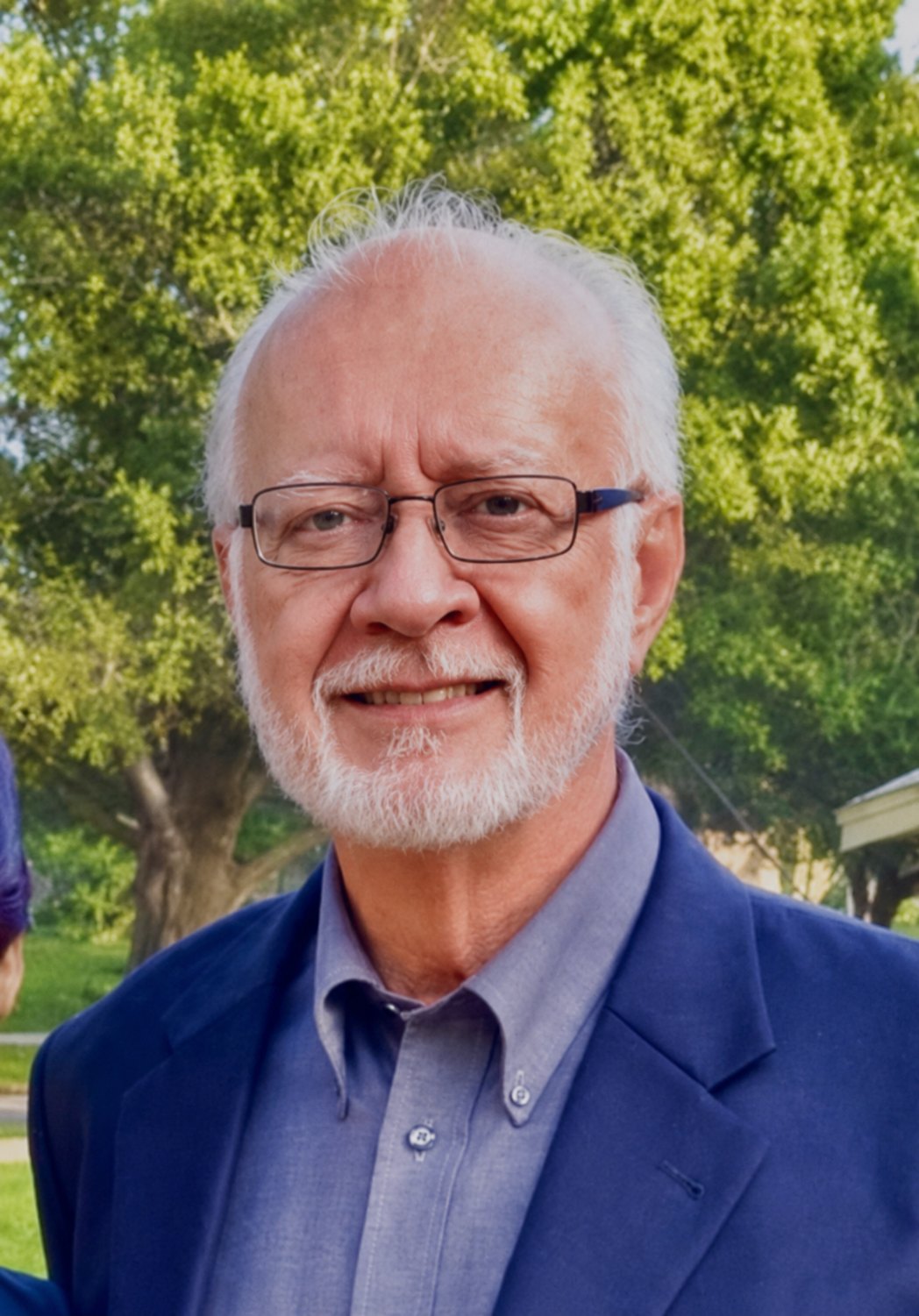 Portrait of Dr. Al Huba, smiling, outdoors beneath a tree.